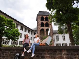 Zwei Studentinnen sitzen auf der Mauer vor dem Hexenturm