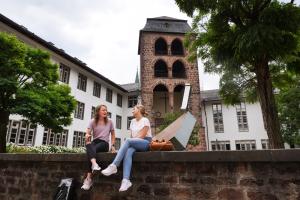 Zwei Studentinnen sitzen auf der Mauer vor dem Hexenturm