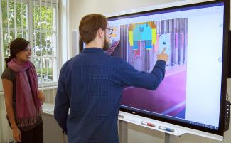 Junge Frau und junger Mann interagieren mit Smartboard