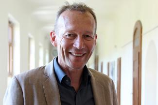 Prof. Dr. Manfred Seidenfuß im Flur des Altbaus der Pädagogischen Hochschule. Er lächelt in die Kamera.