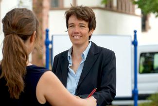 Das Bild zeigt Prof. Dr. Claudia Hildebrand vor der Pädagogischen Hochschule Heidelberg im Gespräch mit einer von hinten sichtbaren Frau. | © PHHD/hop