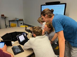 Studierende beugen sich im HSE Digital Teaching and Learning Lab über Laptops bzw. Tablets. Im Hintergrund ein Smartboard.