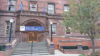 Das Bild zeigt Treppe und Eingang zum Teachers College mit einem blauen Begrüßungsbanner: "Forging a Future. First Gen Celebration Week"er
