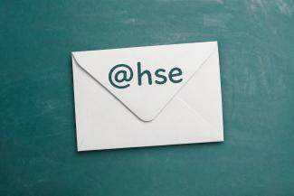Die Grafik zeigt einen weißen Mailumschlag mit Aufschrift "@HSE" auf petrolfarbenem Tafelhintergrund