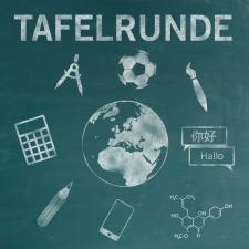 Auf einer petrolfarbenen Tafel steht in Kreide der Titel „TAFELRUNDE“. Darunter eine Weltkugel, um die sich ein Ball, ein Pinsel, Sprechblasen, eine chemische Formel, ein Smartphone, ein Bleistift, ein Taschenrechner und ein Zirkel gruppieren.