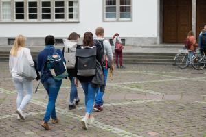 Gruppe Studierender läuft auf die Neue Universität zu