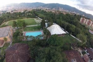 Blick von oben auf das weitläufige grüne Gelände der Deutschen Schule in Medellín mit Kindergartengebäude, Mensa/Kantine, Fußball- und Leichtathletikplatz, Turnhalle, Schwimmbecken und Sportpavillon – im Hintergrund die Stadt, dahinter die Berge | © Tobias Apel