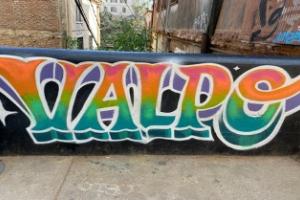 Auf einer Mauer prangt ein farbenfrohes Graffiti mit dem Schriftzug VALPO. 