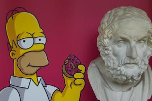 Das Foto zeigt Homer Simpson neben der antiken Büste Homers.