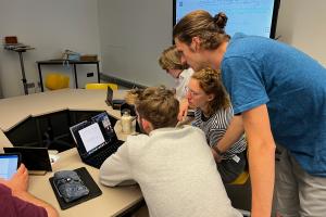 Studierende beugen sich im HSE Digital Teaching and Learning Lab über Laptops bzw. Tablets. Im Hintergrund ein Smartboard.