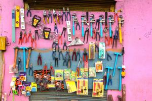 An einer leuchtend pinkfarbenen Wand hängt diverses Werkzeug, Zangen, Hammer, Wasserwaagen etc.