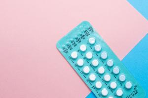 Blisterpackung eines oralen Kontrazeptivums auf rosa/blauem Untergrund.