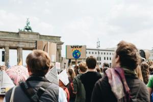 Vor dem Brandenburger Tor demonstrieren jungen Menschen für mehr Klimaschutz. Ein Plakat zeigt eine Erde in Flammen mit dem Text WAKE UP.
