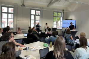 Teilnehmende des Zukunftsforums sitzen an Tischen gruppiert im KOnferenzraum der HSE. Am Smartboard stehen Dr. Dennis Dietz, Dr. Daniel Vetter und Dr. Lina Pranaityte