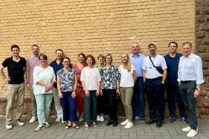 Gruppenbild von 14 Mitgliedern der AG Querschnittskompetenzen vor einer Mauer