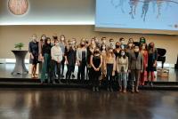 Gruppenfoto der Absolvent:innen des Master of Education, Profillinie Lehramt Gymnasium sowie M. Ed. Gerontologie, Gesundheit & Care auf der Bühne der Neuen Universität