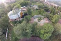 Inmitten von vielen Grünflächen und Bäumen verschiedene Gebäude der Deutschen Schule Medellin, Kolumbien: in der Mitte des Bildes der Pavillon der Oberstufe mit reichlich Sitzgelegenheit in der Pause im Freien, rechts oben die Bibliothek, links das Auditorium Maximum und hinten der Parkplatz. | © Tobias Apel