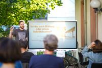 Über die Köpfe der Gäste hinweg ist Referent Matthias Heil auf der Terrasse der Heidelberg School of Education zu erkennen; er steht vor dem Smartboard, auf dem der Veranstaltungstitel „Ist das noch Bildung oder schon Indoktrination?“ zu lesen ist.