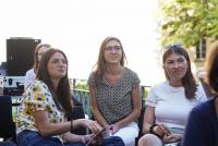 Vier Studentinnen lauschen auf der HSE-Terrasse interessiert dem Vortrag. Im Hintergrund ein Baum und technisches Equipment.