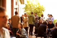 Auf der ins Abendlicht getauchten Terrasse der Heidelberg School of Education sitzen und stehen Menschen verschiedenen Alters, die in angeregte Gespräche vertieft sind.