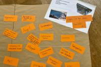 Orangefarbene Antwortkärtchen der Teilnehmenden zur Frage nach Zukunftsfundamenten liegen auf einem Papier auf dem Parkettboden.  Bild: © Heidelberg School of Education | Isis Giebel