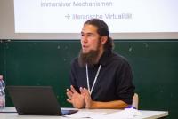 Dr. Florian Nieser bei seinem Impuls zu Transmedialer Mediävistik vor einer Tafel, oberhalb ist die Vortragsleinwand zu erkennen. Bild: © Heidelberg School of Education | Vanessa Bender