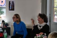 Marita Friesen und Michael Haus sitzen im US-amerikanisch dekorierten Konferenzraum lachend nebeneinander.