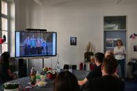 Christiane Wienand zeigt auf dem Smartboard Bilder aus Michael Haus' Amtszeit, hier ein Gruppenbild von Uni- und PH-Kolleg:innen mit den Kooperationspartnern des Teachers College.