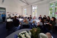 Das HSE-Team lauscht an Tischen im US-amerikanisch dekorierten Konferenzraum Marita Friesens Rede.