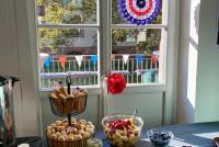 Amerikanisch inspiriertes Buffet mit Cookies und Hotdogs, an der Fensterscheibe USA-Dekoration