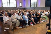 Das Bild zeigt ein lachendes Publikum in der Festhalle der PH Heidelberg. 