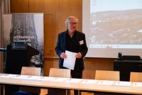 Prof. Dr. Michael-Jörg Oesterle steht hinter Tischen, auf denen Blätter und Stifte zum Unterzeichnen ausgelegt sind. In den Händen ein Papier.