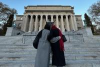 Zwei von hinten aufgenommene junge Frauen steigen Arm in Arm die Treppe vor der Columbia University Library hoch.