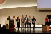 Prof. Dr. Silke Hertel und Dr. Christiane Wienand mit Absolvent:innen auf der Bühne. Sie halten ihre Zeugnisse in den Händen.