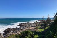 Meer, Felsen und grün bewachsene Küstenlandschaft unter blauem Himmel