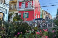 Bunte Häuser in Valparaíso, davor blühende Pflanzen und Graffiti.