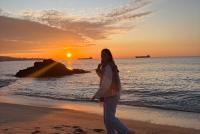 Eine junge Frau spaziert im Sonnenuntergang am Strand von Vina del Mar.