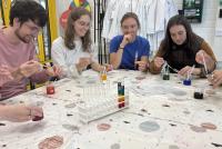 Teilnehmende der Future-Literacies-Projektwoche experimentieren im LUMA-Zentrum mit verschieden gefärbten Flüssigkeiten, um deren Dichte sichtbar zu machen. Es entsteht ein „Regenbogen im Reagenzglas“.
