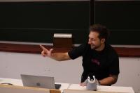 Prof. Dr. Andreas Dengel demonstriert bei seiner Keynote, wie man die KI trainiert, die Anzahl gezeigter Finger zu erkennen.